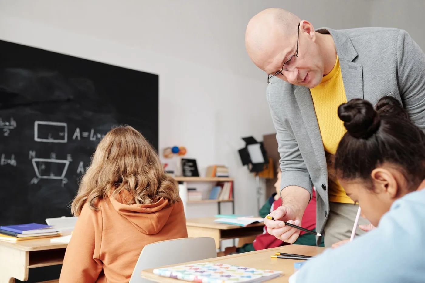 Asistent pedagoga vede žáka při samostatné práci ve třídě.