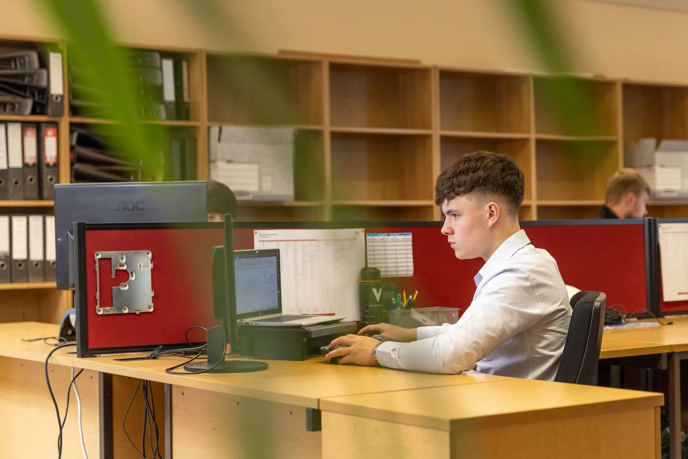 Zaměstnanec soustředěný na práci u počítače v kanceláři.
