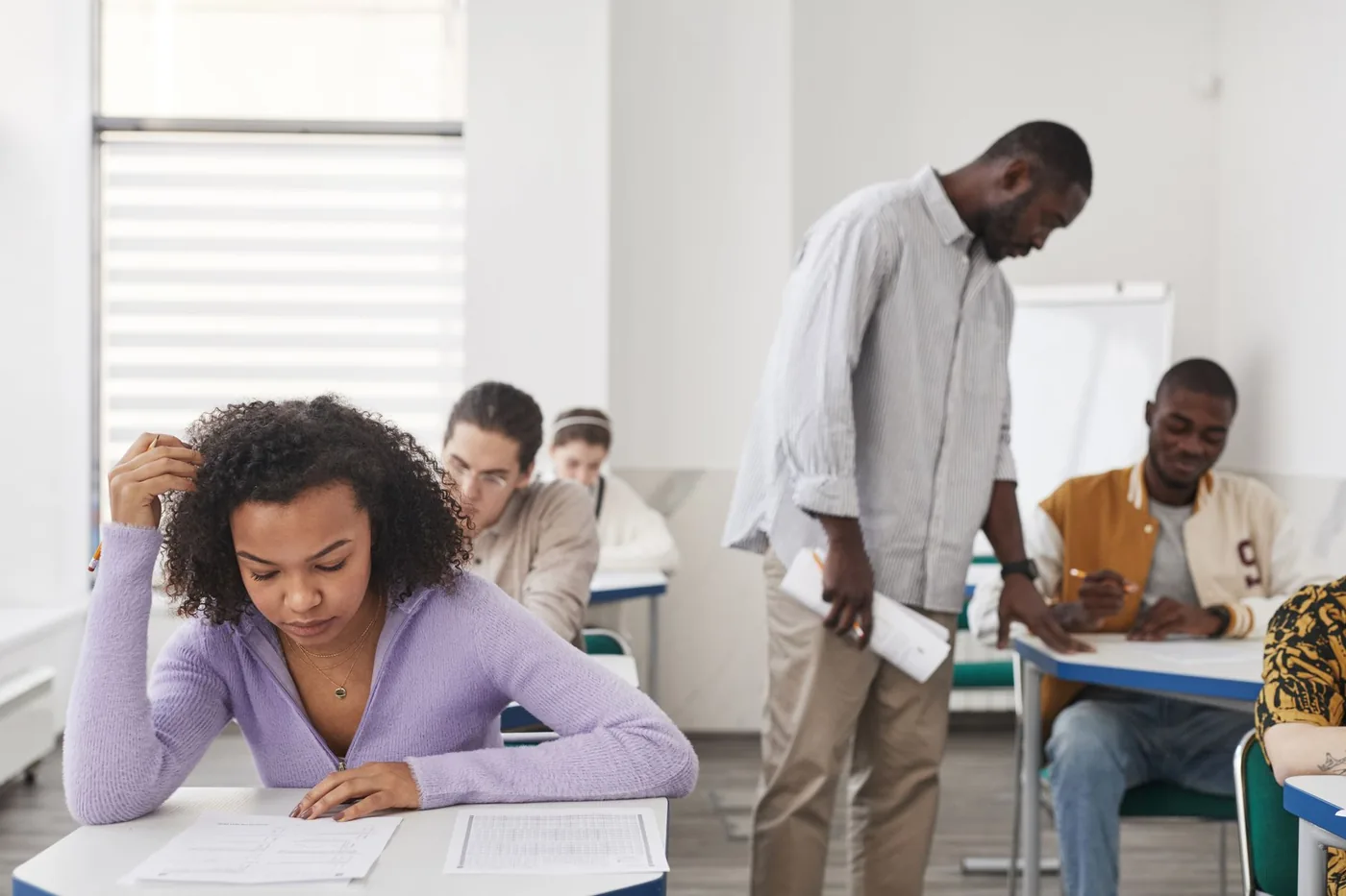 Student soustředěně vypracovává test v lavici během přijímací zkoušky.